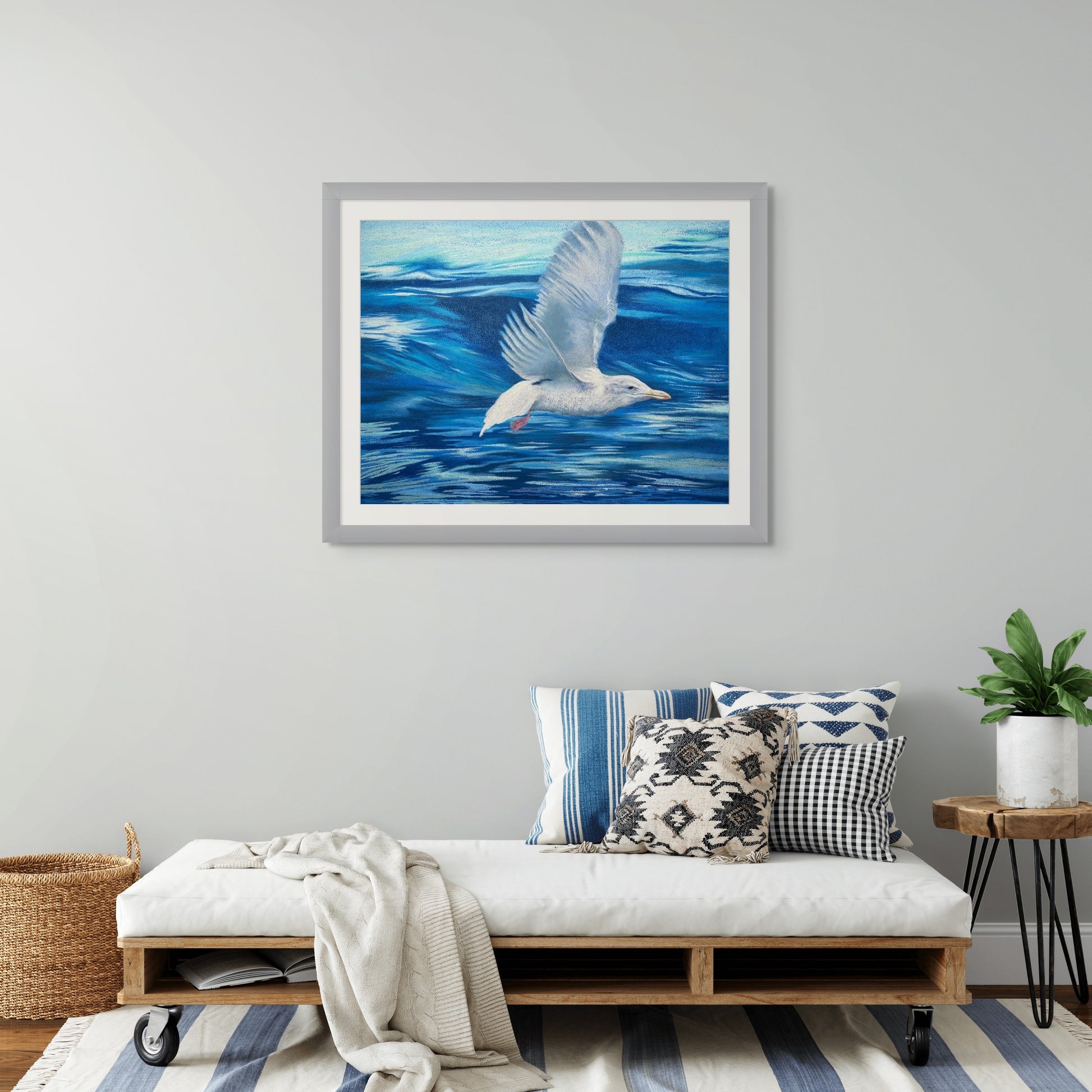 Room mockup of Crest of the Wave, a framed coastal bird painting by Georgia Edwards displayed above a daybed in a bright modern interior.